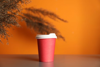 Photo of Paper cup on grey table indoors. Mockup for design