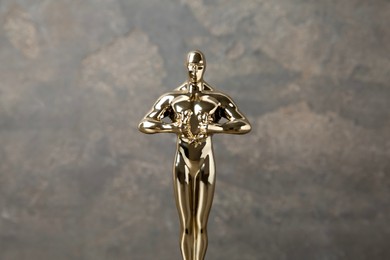 Photo of Golden trophy in shape of human figure against blurred gray background