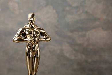 Photo of Golden trophy in shape of human figure against blurred gray background, space for text