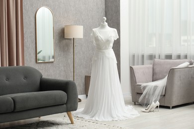 Photo of Beautiful wedding dress on mannequin and shoes in boutique