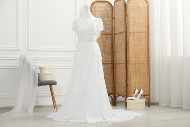 Photo of Beautiful wedding dress on mannequin and shoes in boutique