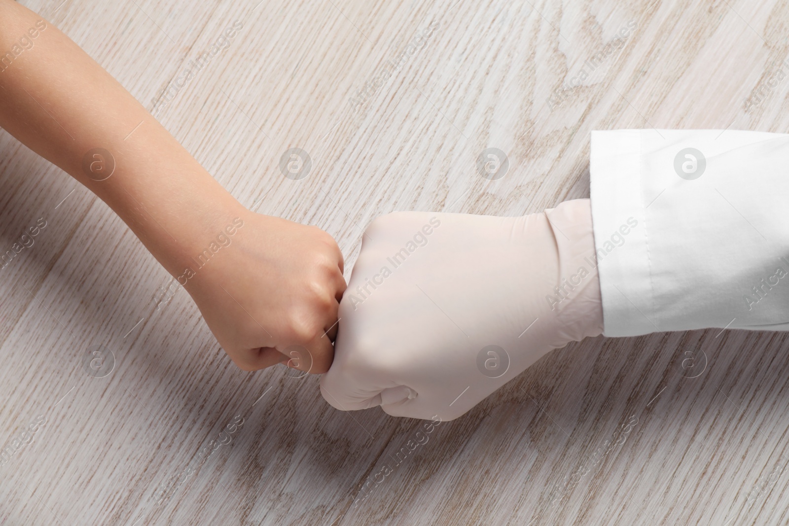 Photo of Doctor and child at white wooden table, top view