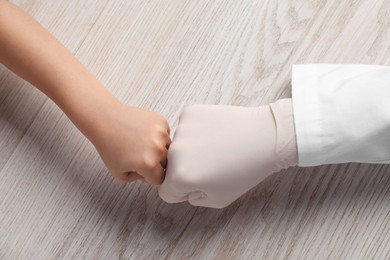 Photo of Doctor and child at white wooden table, top view