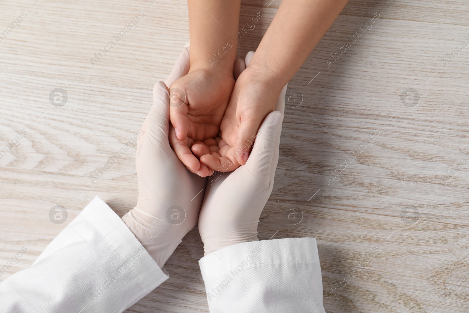 Photo of Doctor and child at white wooden table, top view