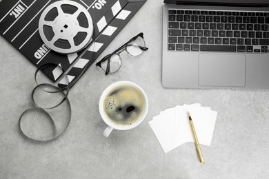 Photo of Flat lay composition with movie clapper, film reel and laptop on grey textured table