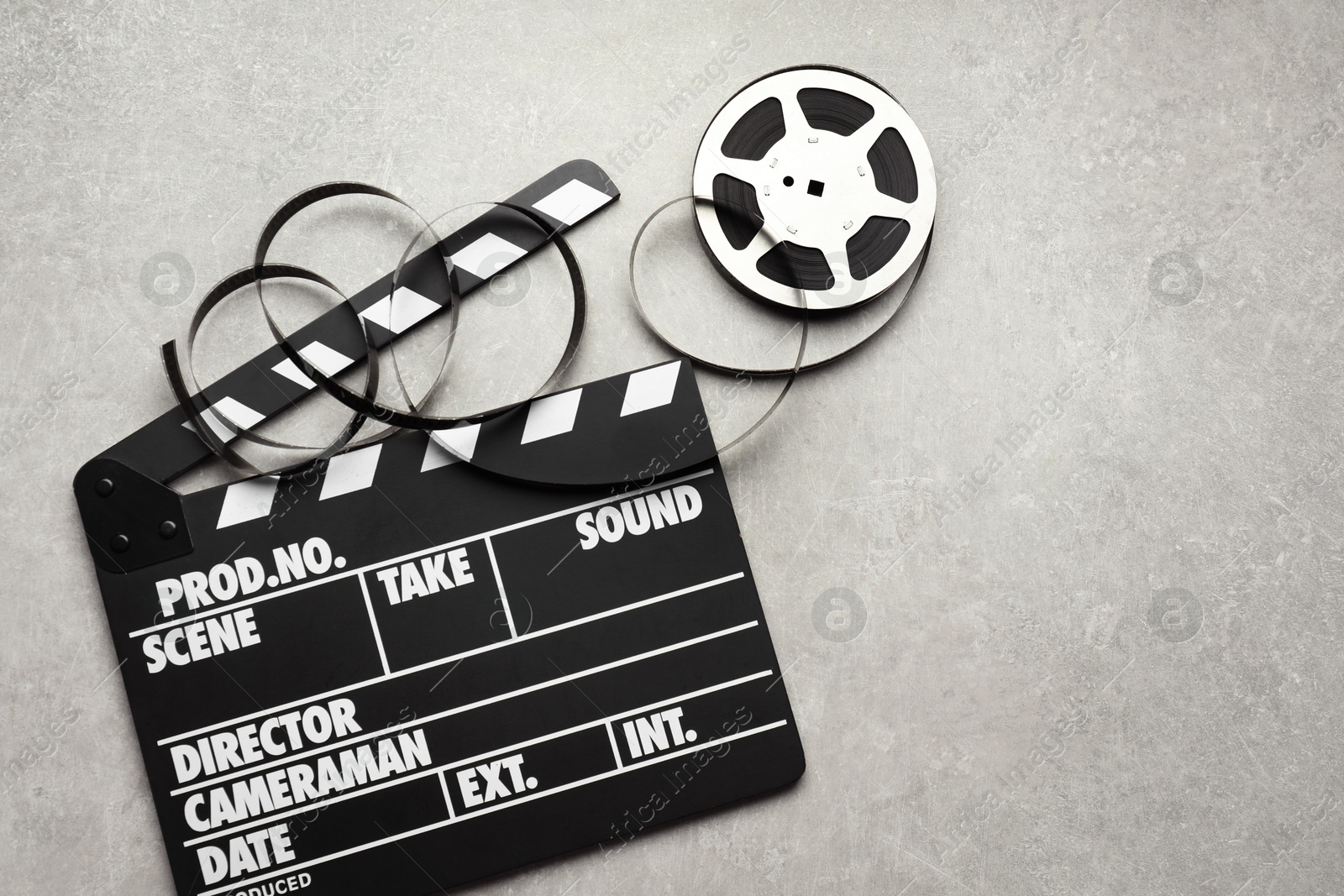 Photo of Movie clapper and film reel on grey textured table, flat lay