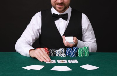 Professional croupier with playing cards at gambling table, closeup