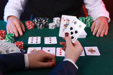 Photo of Professional croupier and gambler at table with playing cards and casino chips, closeup