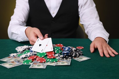 Photo of Professional croupier holding playing cards at gambling table with casino chips and money, closeup