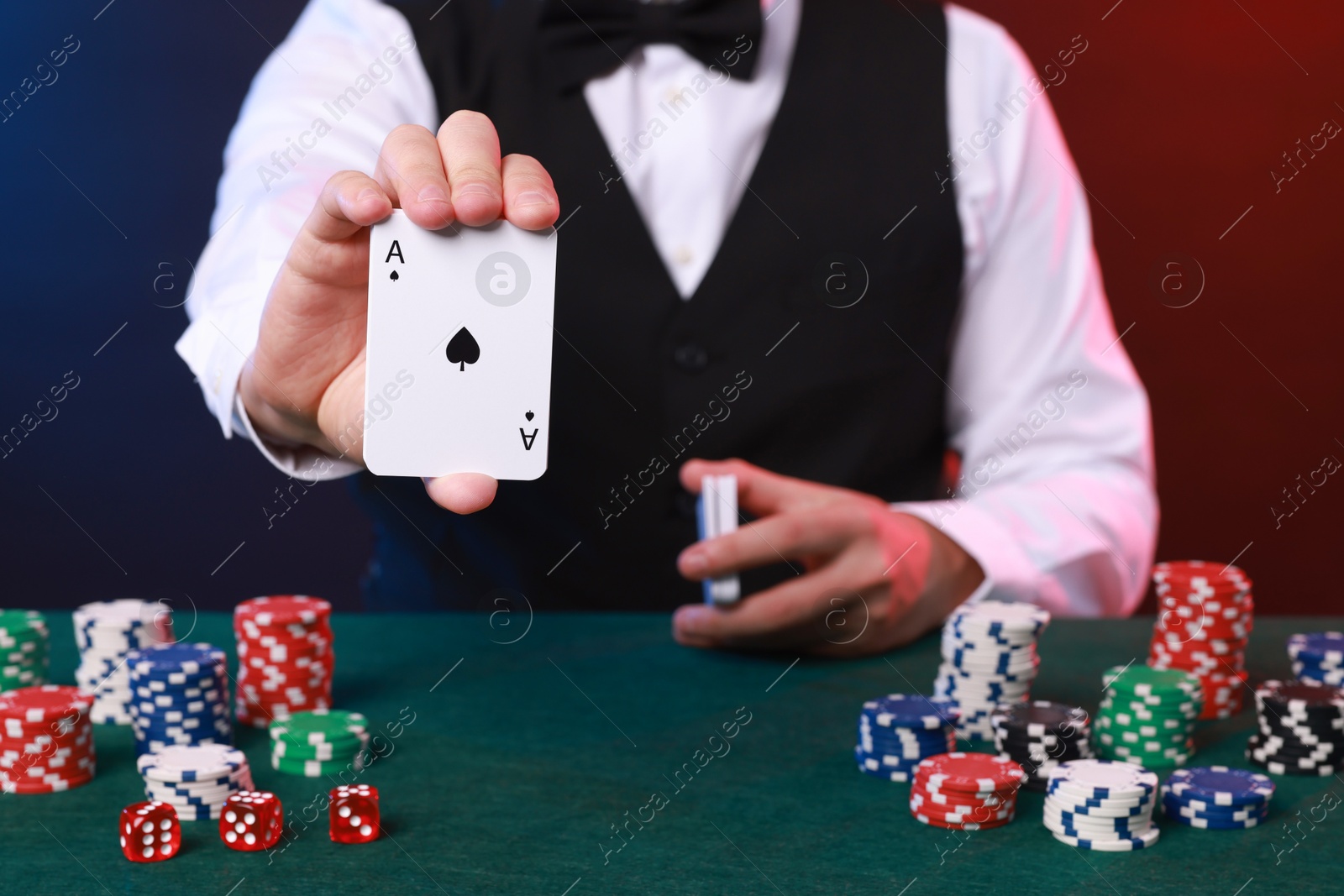 Photo of Professional croupier with playing cards at gambling table, closeup