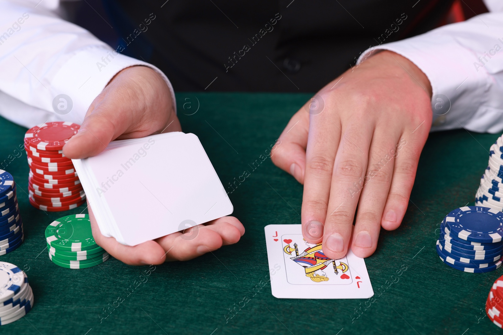 Photo of Professional croupier with playing cards at gambling table, closeup