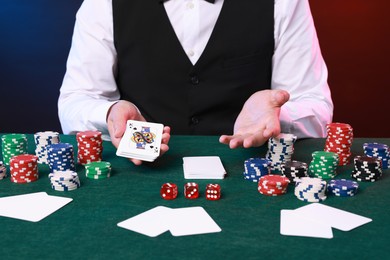 Photo of Professional croupier with playing cards at gambling table, closeup