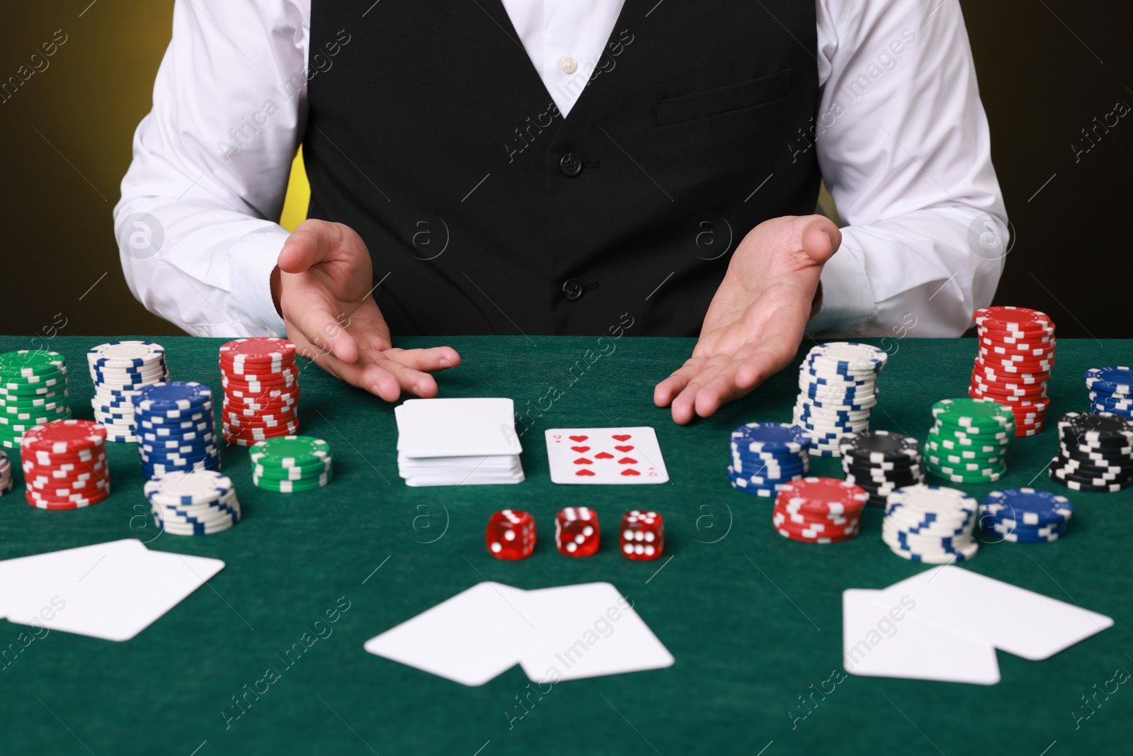 Photo of Professional croupier at gambling table with casino chips, playing cards and dice, closeup