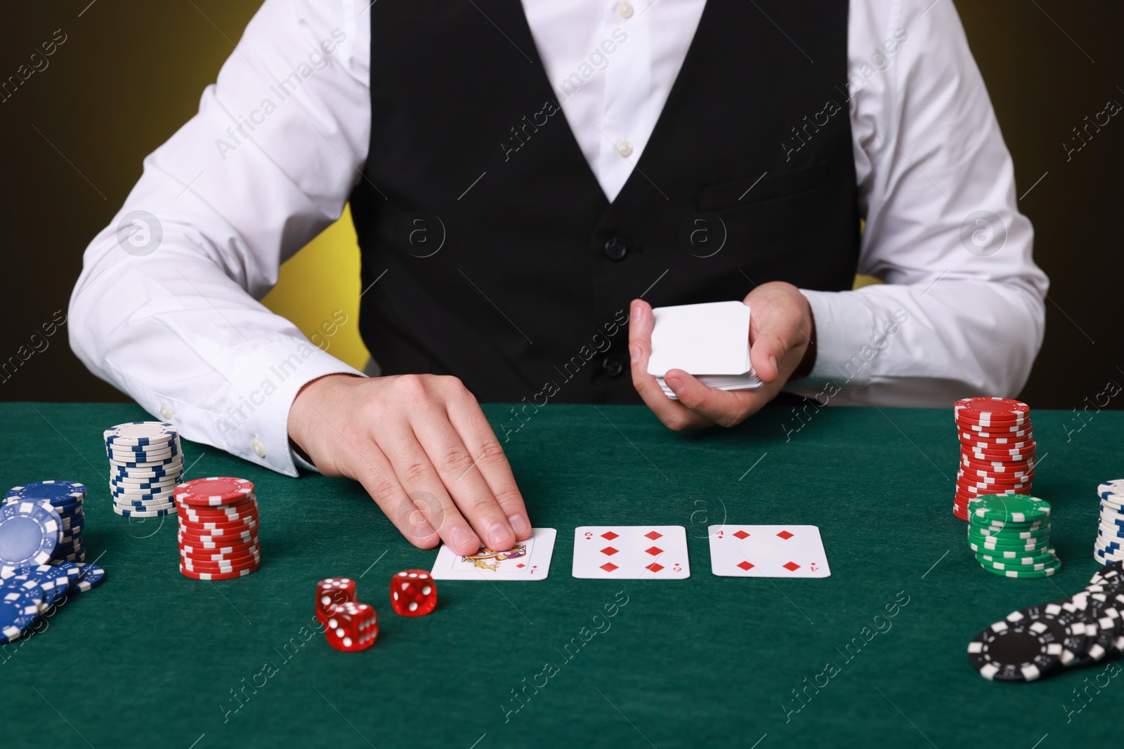 Photo of Professional croupier with playing cards at gambling table, closeup