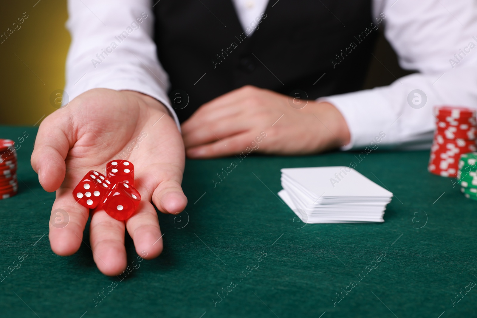 Photo of Professional croupier with dice at gambling table, closeup