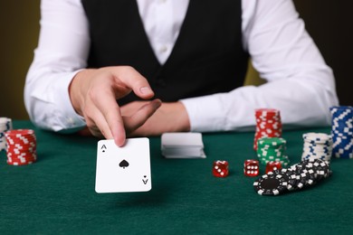 Photo of Professional croupier with playing card at gambling table, closeup