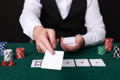 Photo of Professional croupier with playing cards at gambling table, closeup