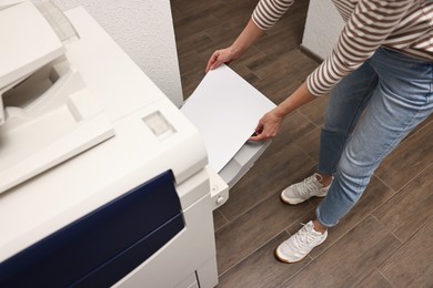 Photo of Woman using modern printer indoors, closeup. Printing house