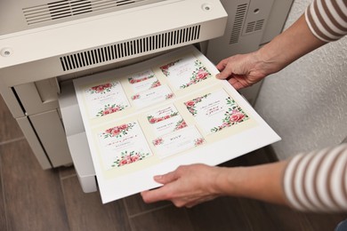 Photo of Woman using modern printer indoors, closeup. Printing house