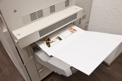 Photo of Modern printer with paper indoors, closeup. Printing house