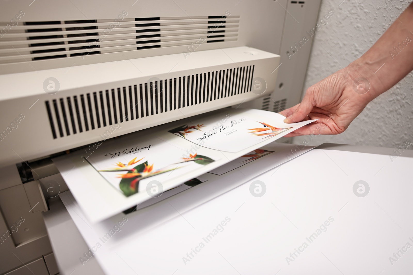 Photo of Woman using modern printer indoors, closeup. Printing house