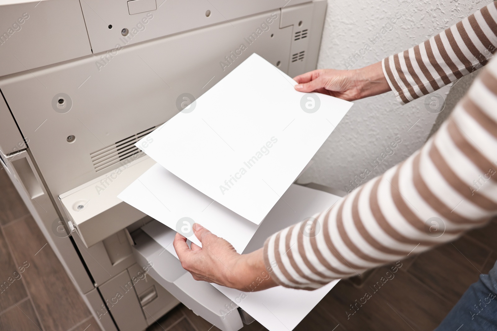 Photo of Woman using modern printer indoors, closeup. Printing house