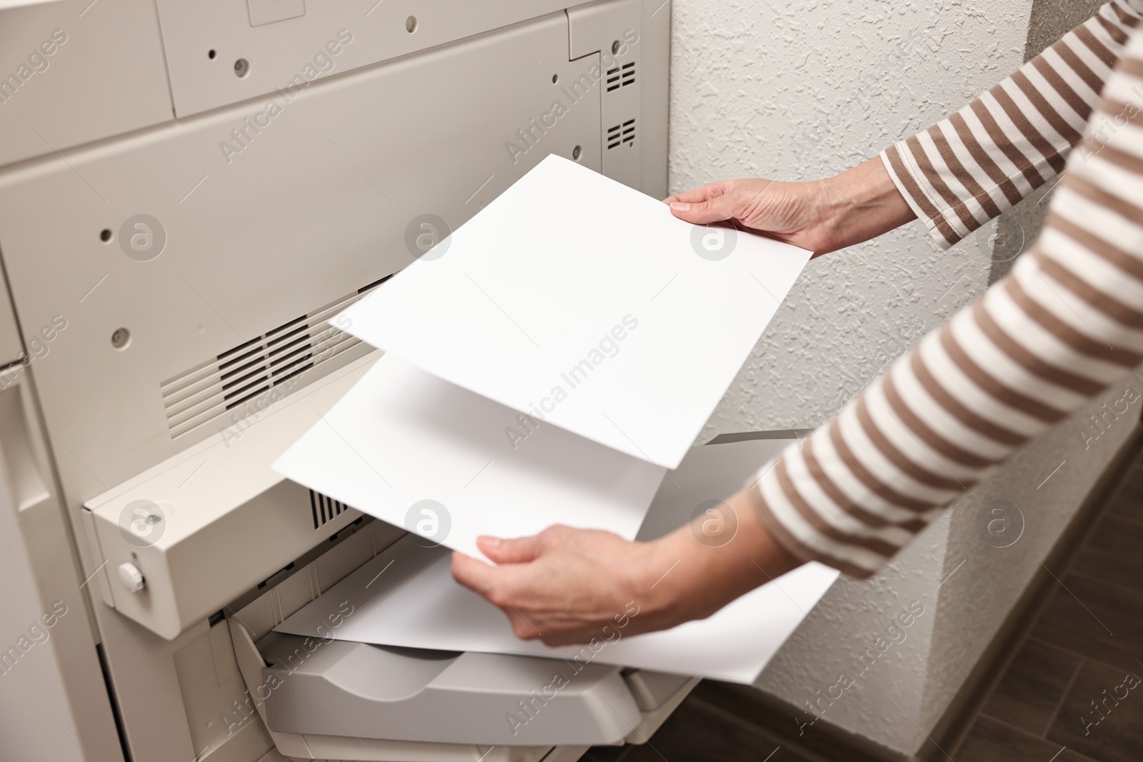 Photo of Woman using modern printer indoors, closeup. Printing house