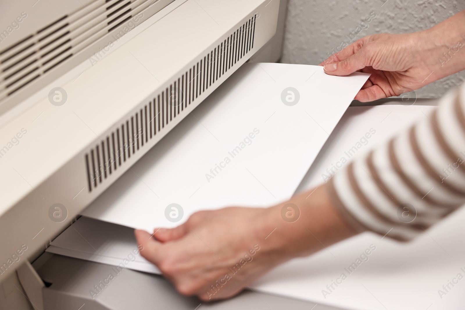 Photo of Woman using modern printer indoors, closeup. Printing house