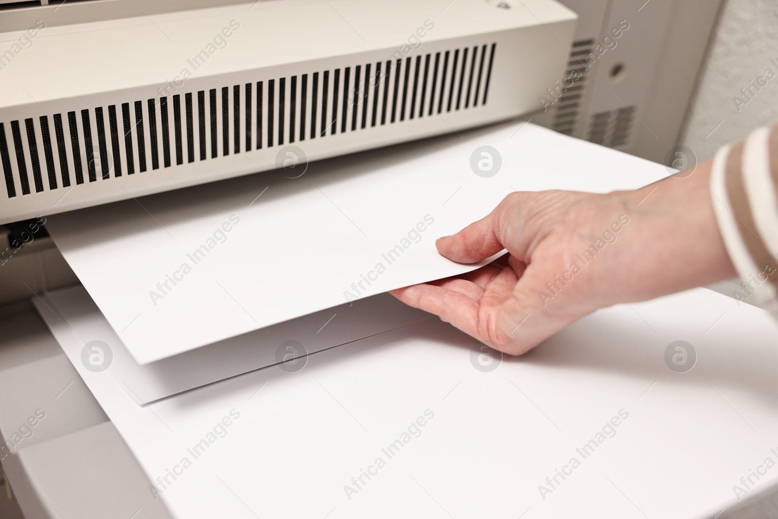 Photo of Woman using modern printer indoors, closeup. Printing house