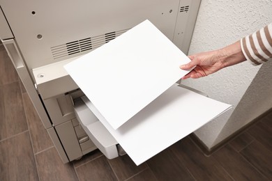 Woman using modern printer indoors, closeup. Printing house