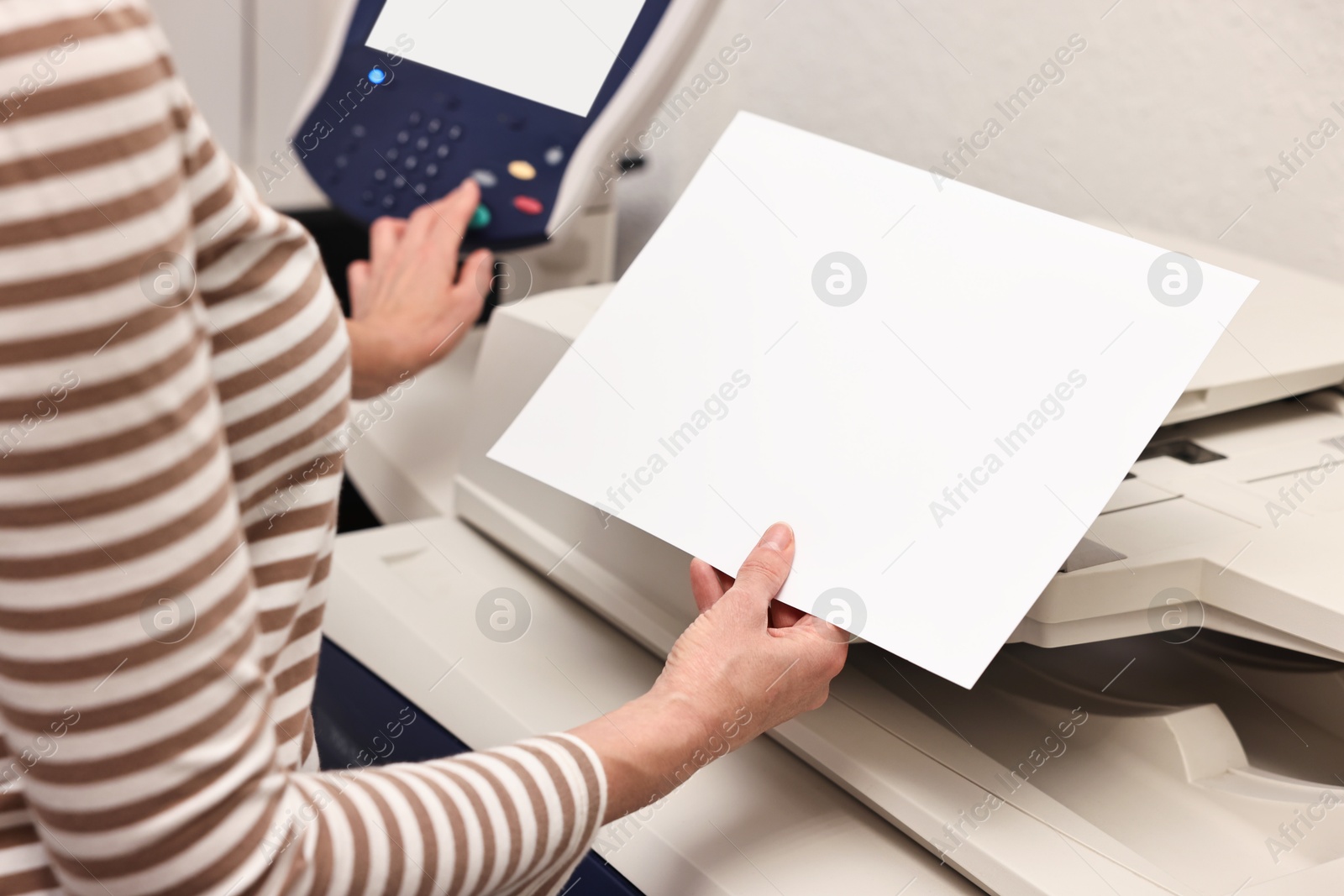 Photo of Woman with paper sheet using modern printer indoors, closeup. Printing house