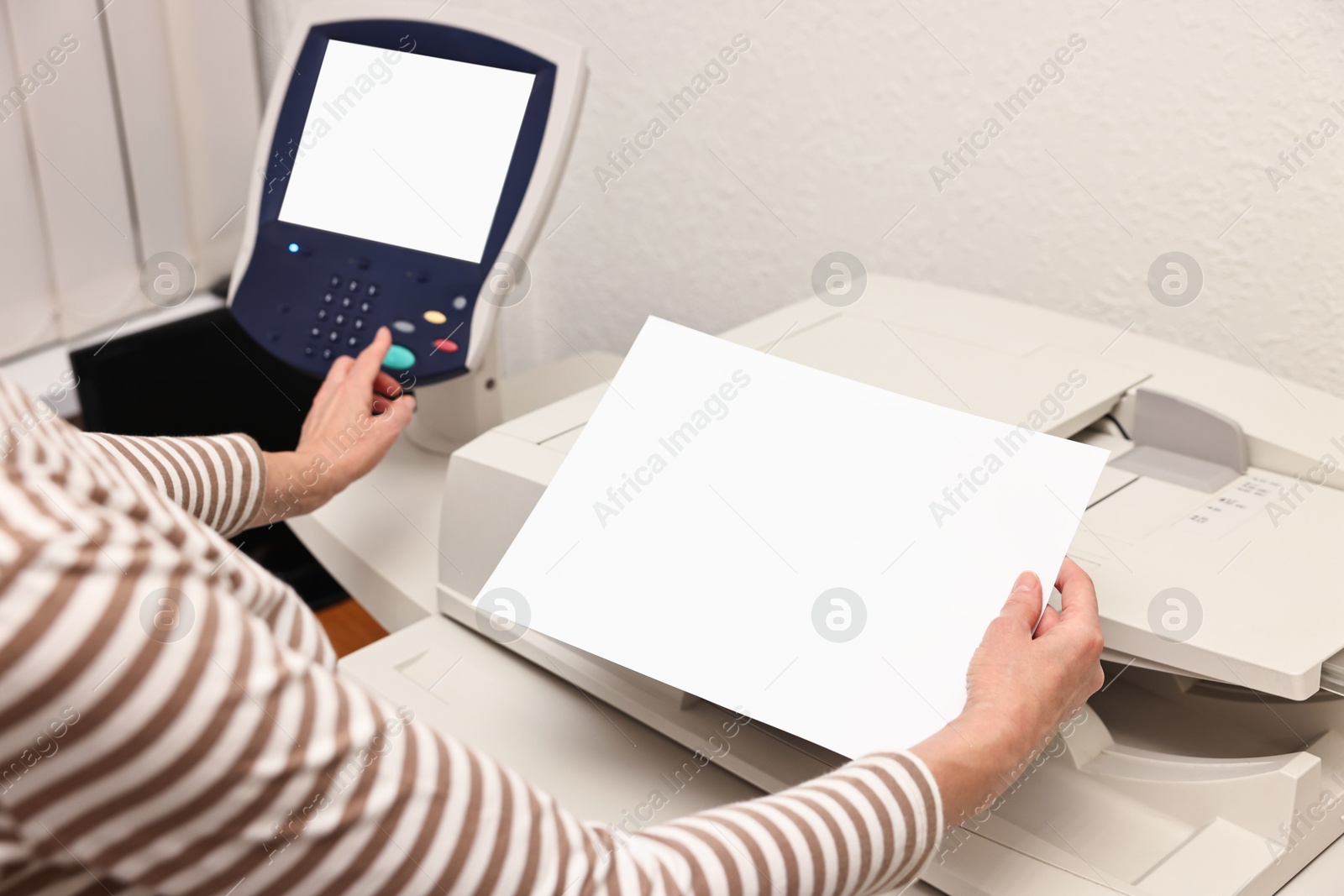 Photo of Woman with paper sheet using modern printer indoors, closeup. Printing house