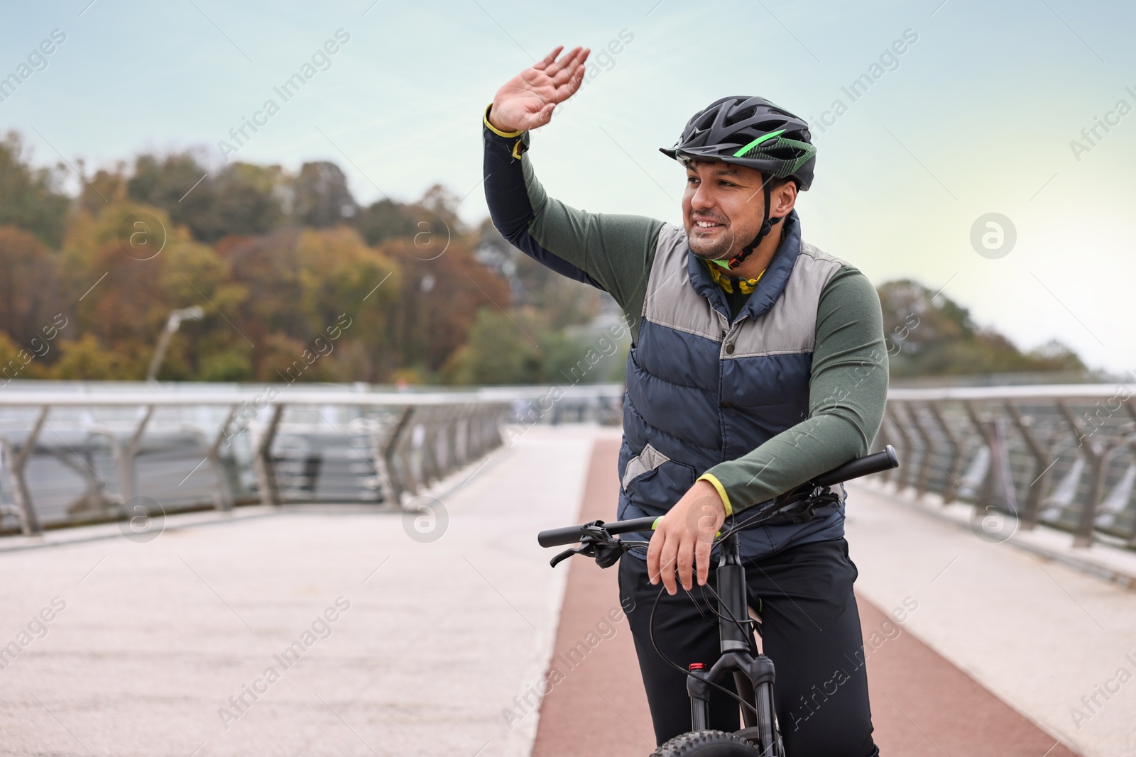 Photo of Man with helmet and bicycle outdoors, space for text