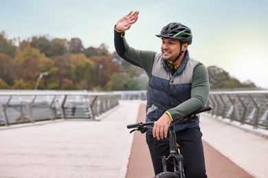 Photo of Man with helmet and bicycle outdoors, space for text