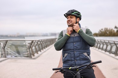 Photo of Man with helmet and bicycle outdoors, space for text