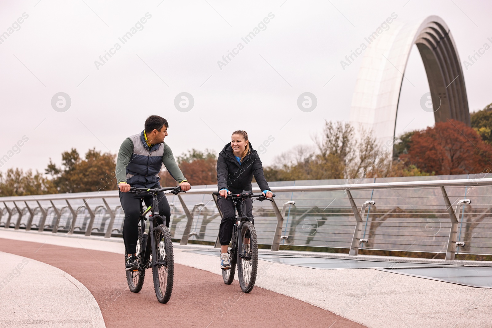 Photo of Beautiful happy couple riding bicycles and spending time together outdoors, space for text