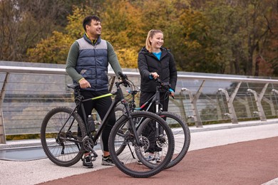 Photo of Beautiful happy couple with bicycles spending time together outdoors, space for text