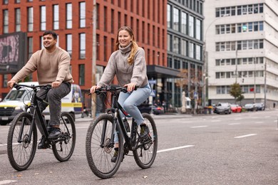 Photo of Beautiful happy couple riding bicycles and spending time together outdoors, space for text