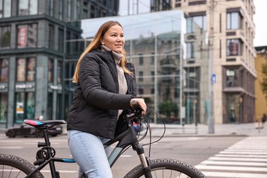 Photo of Woman with bicycle outdoors, space for text