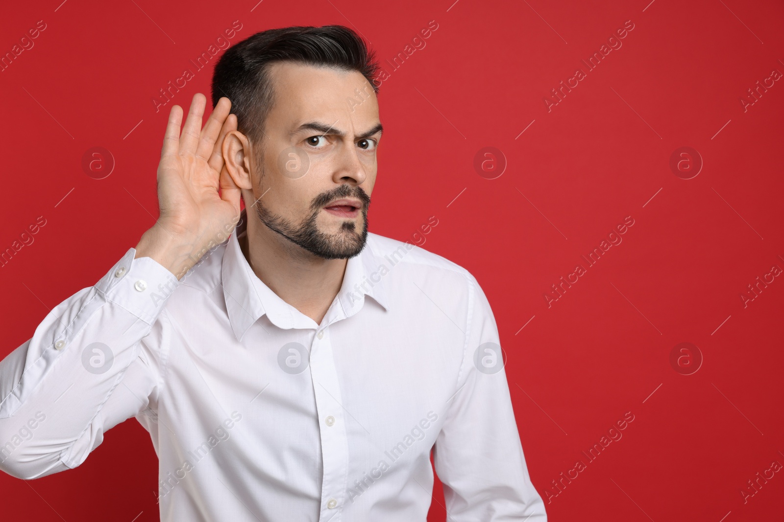 Photo of Man showing hand to ear gesture on red background, space for text