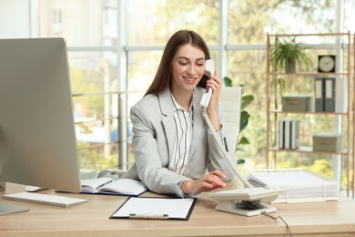 Photo of Banker talking on telephone at table in office