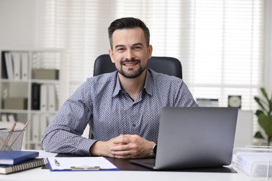 Portrait of smiling banker at table in office