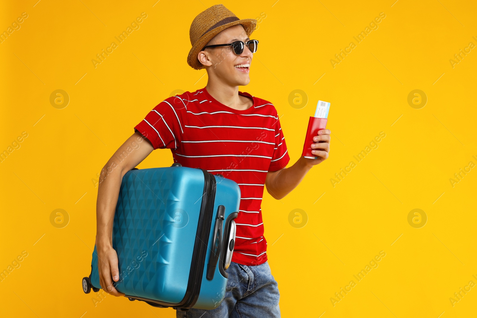 Photo of Happy traveller with suitcase, passport and ticket on yellow background