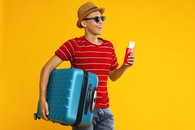 Photo of Happy traveller with suitcase, passport and ticket on yellow background