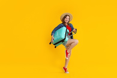 Photo of Happy traveller with suitcase on yellow background