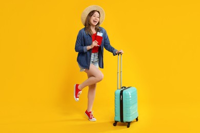 Photo of Happy traveller with suitcase, passport and ticket on yellow background