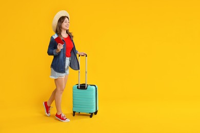 Photo of Happy traveller with suitcase, passport and ticket on yellow background, space for text