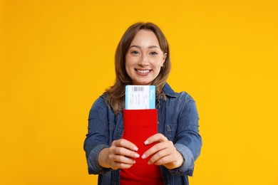 Happy traveller with passport and ticket on yellow background