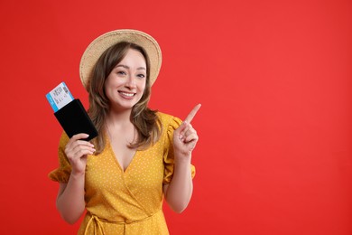 Photo of Happy traveller with passport and ticket pointing at something on red background, space for text