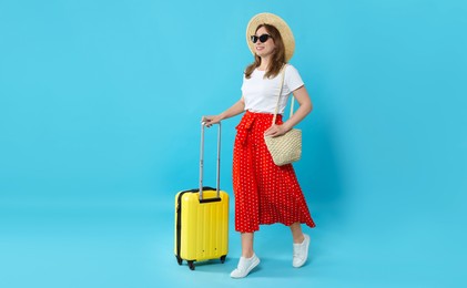 Photo of Happy traveller in sunglasses with suitcase on light blue background